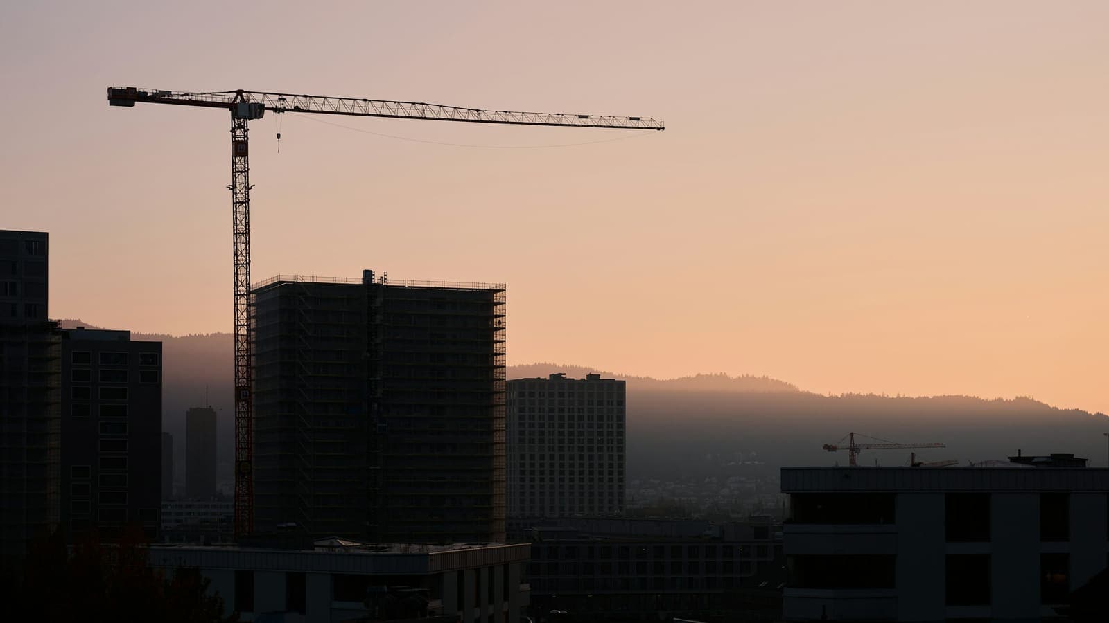 Construction site at dusk with crane silhouette