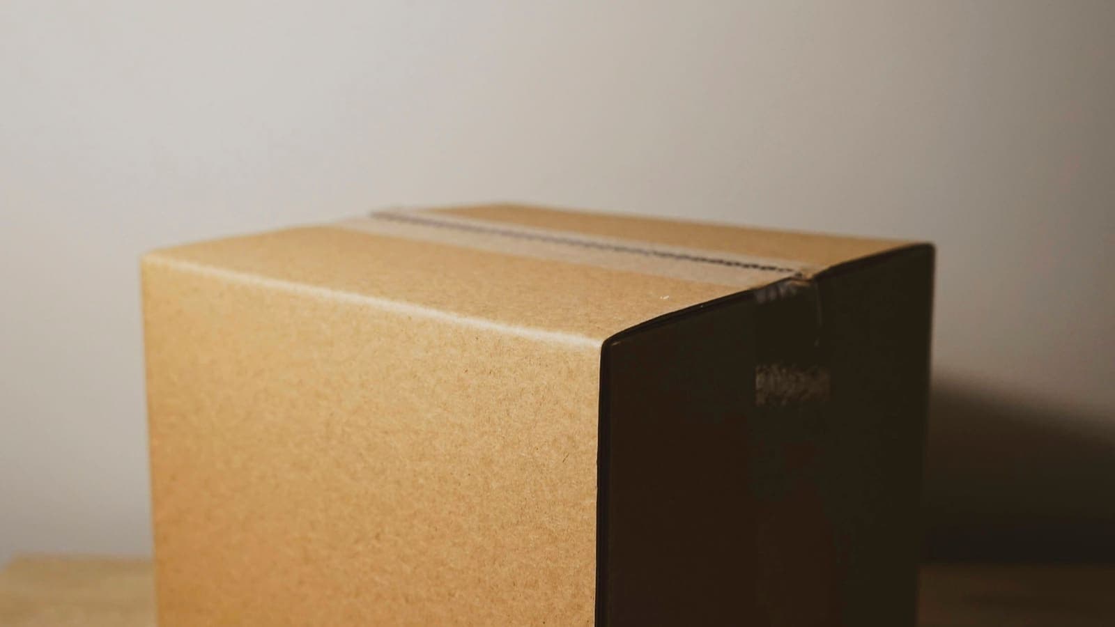 Hands sealing a cardboard shipping box with packing tape